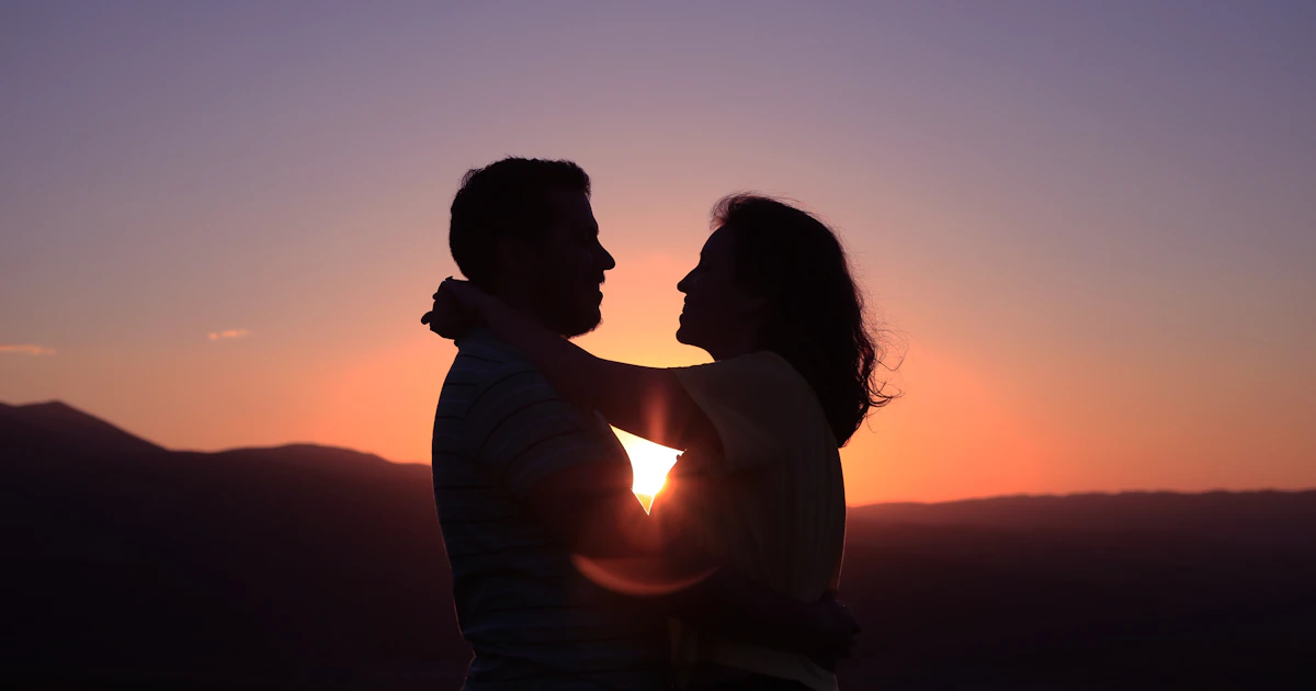 Two people laughing over coffee, the easy warmth of a date going well
