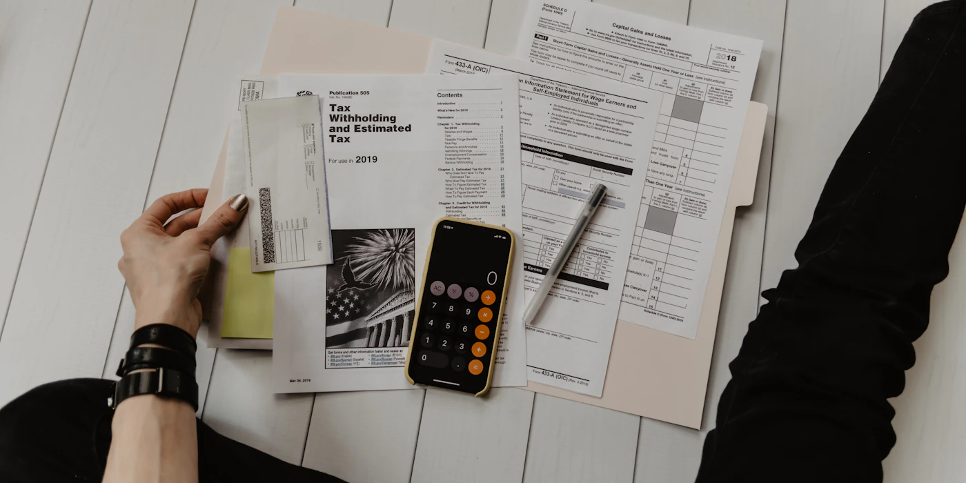 A hand holding a phone with an app-store payment screen, on a desk with a notebook and pen