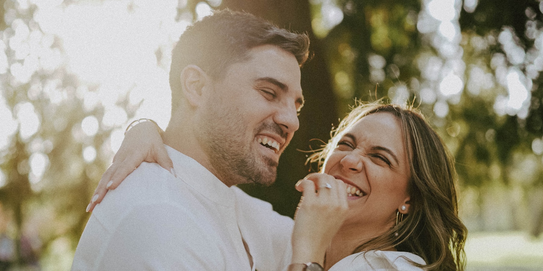 A couple laughing together outdoors in warm afternoon light